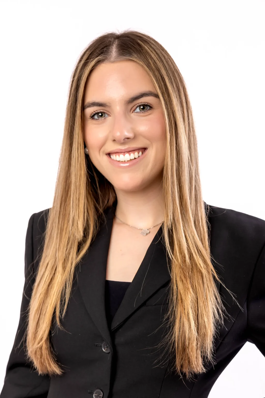 A young woman with long straight blonde hair, wearing a black blazer, smiles at the camera against a plain white background.